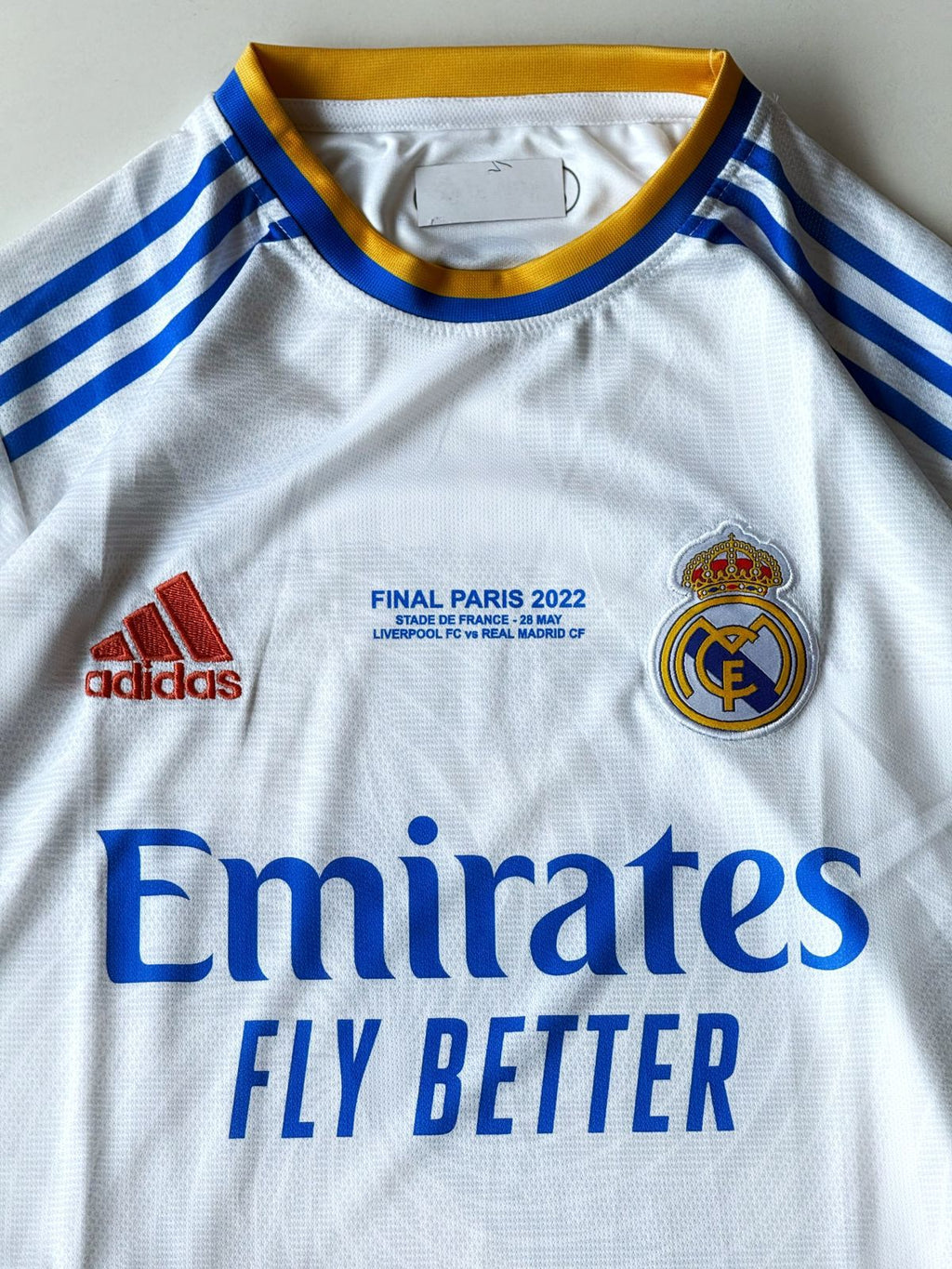 Close-up of the Real Madrid 2021 2022 UCL Final Paris home jersey showing the gold match embroidery, club crest, and embroidered brand logo at vamstore India.